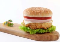 layered burger on top of wooden board